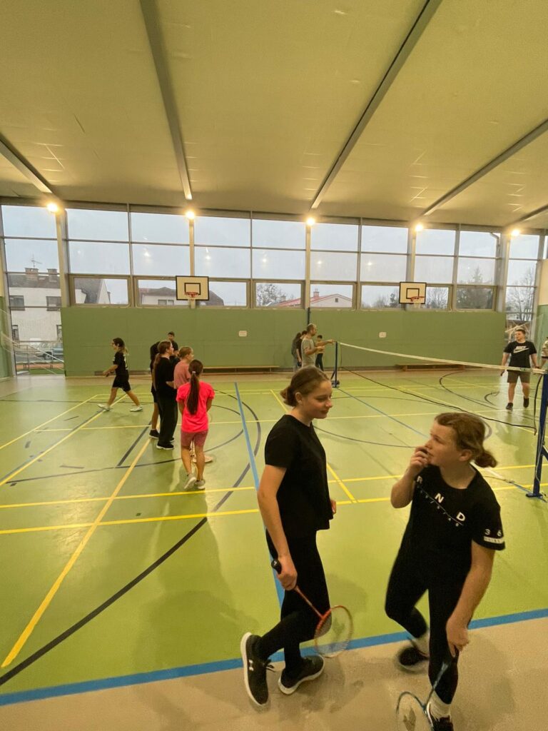 žáci hrající badminton po celé tělocvičně