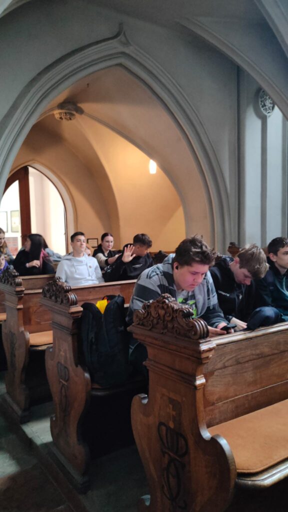 žáci uvnitř kostela sedící na lavicích