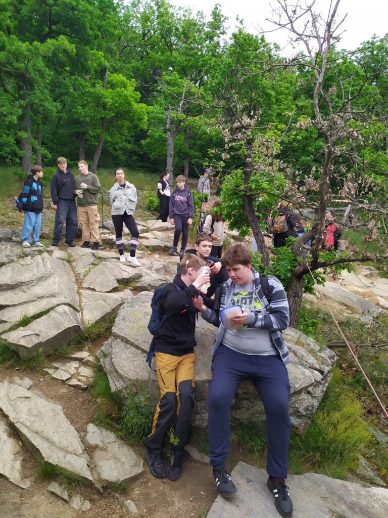žáci sedící na kamenech a stojících také